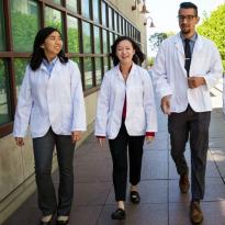 students wearing white coats and walking