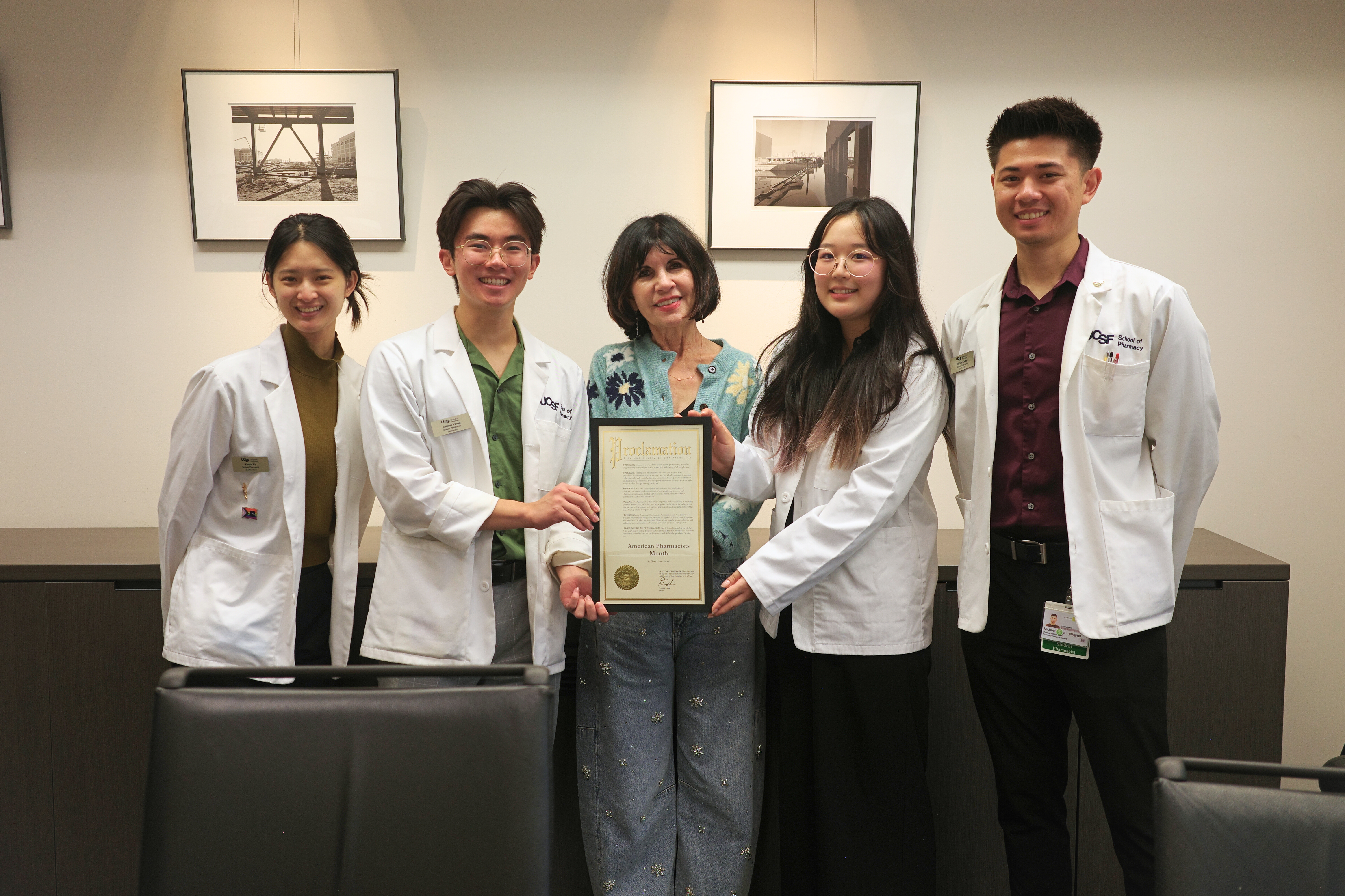 Dean Giacomini holding a certificate, standing with PharmD students