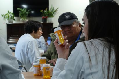 Student holding prescription bottle with patient
