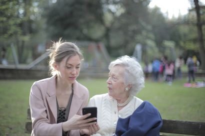 Two woman conversing while one holds a cell phone