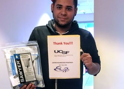 staff member holds one water filter and a thank you note.