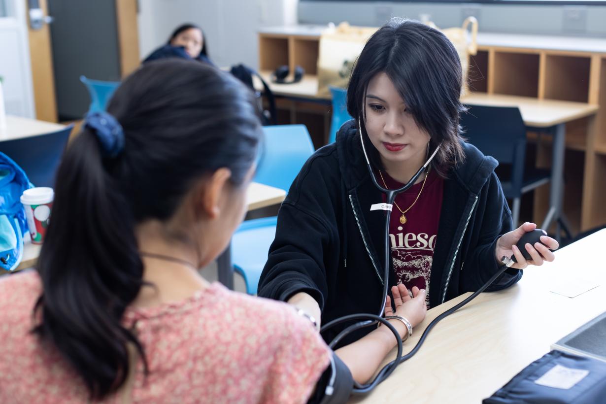 student takes the blood pressure of a patient.