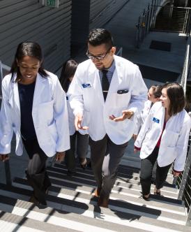 Students in white coats walking up some stairs