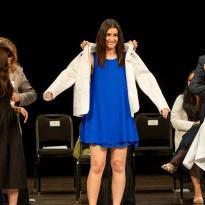 students don white coats at a ceremony.