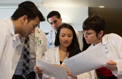 PharmD students look at papers with a faculty member