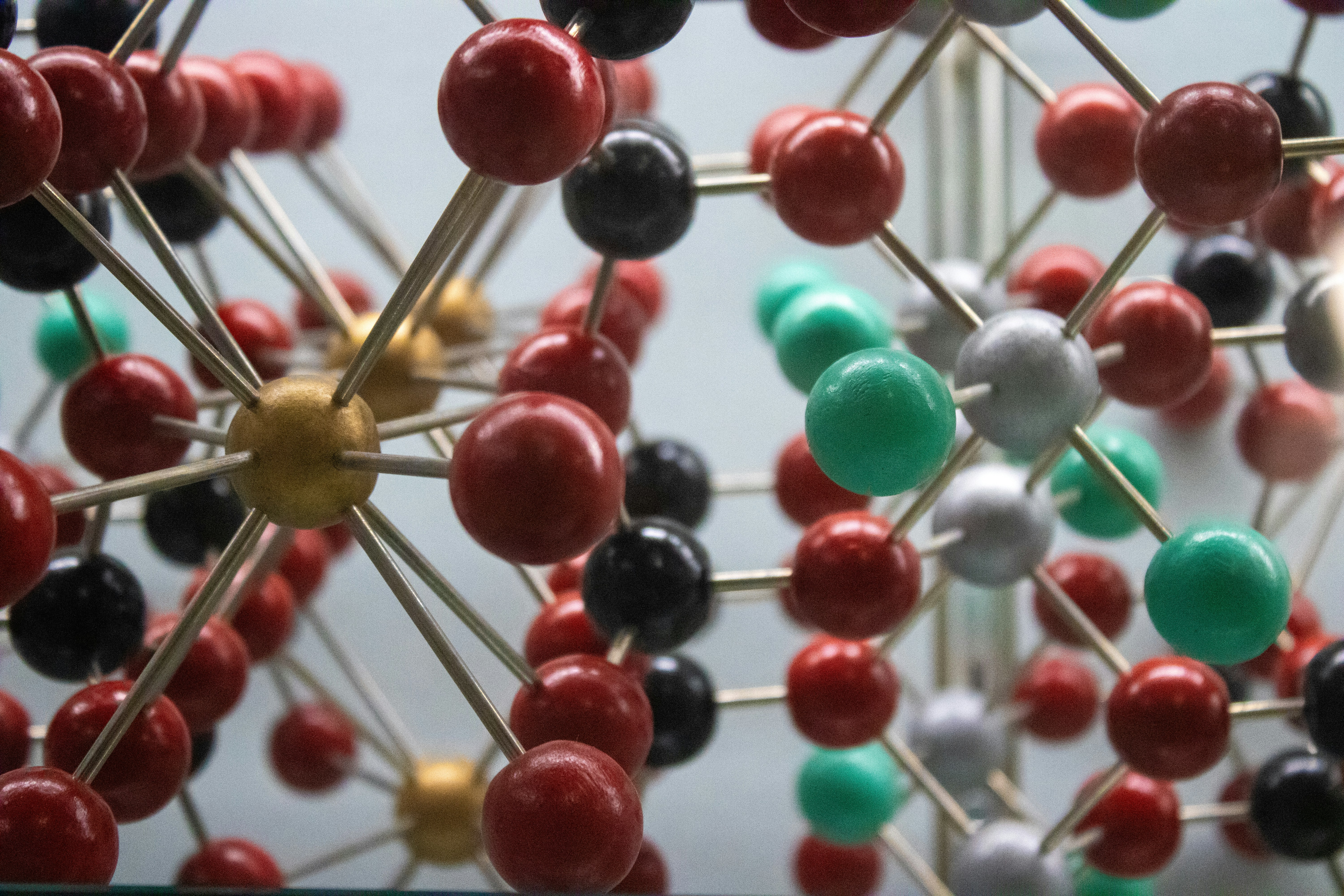 molecular structure, illustrated in large form with metal rods conneteing red, green, white black and whicte balls in a zoomed in, incomplete view