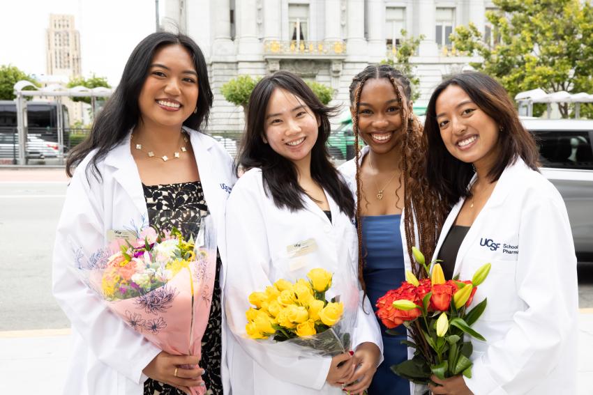 group of PharmD students with white coats and flowers