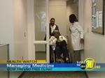 a patient in a wheelchair is pushed by another person while a health care provider holds a door open