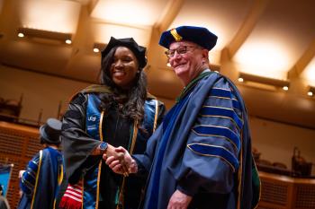 A graduate poses with UCSF Chancellor Sam Hawgood, MBBS