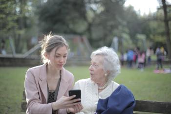 Two woman conversing while one holds a cell phone