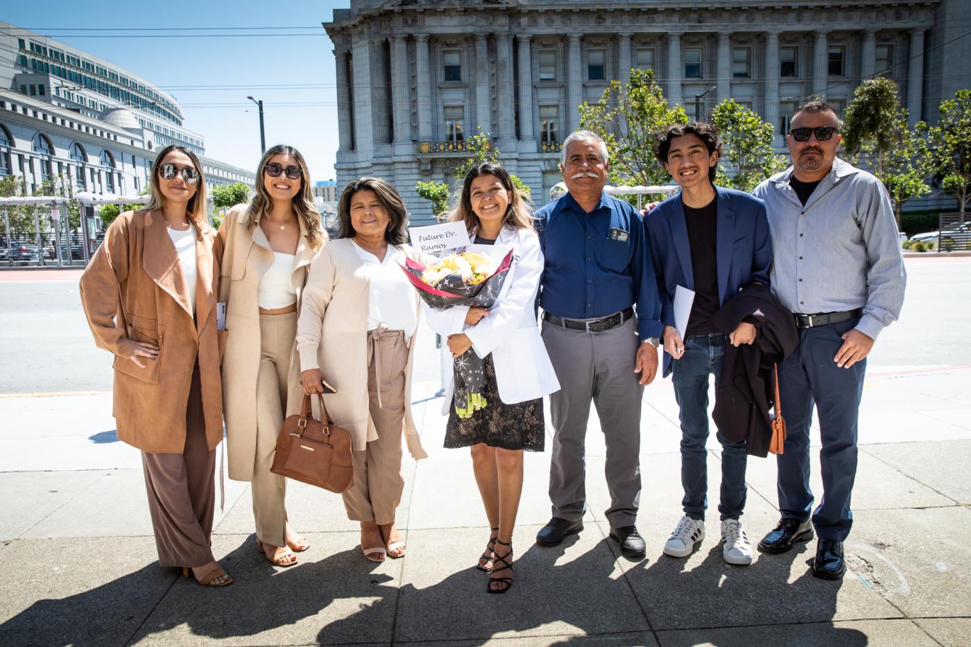 six family members surround a student in white coat holding a "Future Dr. Ramos" sign.